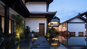 A traditional Japanese-style building with a wooden door, a water wheel, and a stone pathway leading to the entrance. - LA MAISON . View Resort (Lijiang)