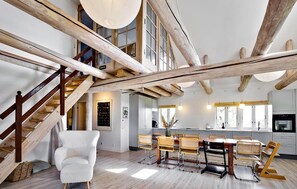 A spacious loft with exposed wooden beams, a dining area with a large table and chairs, and a staircase leading to an upper level. - 3 bedroom stunning home in Hundested (Hundested)