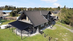 Une maison moderne avec un toit en pente, un espace extérieur couvert et une cour clôturée.