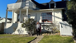 A two-story house with a balcony, a stone pathway, and a white picket fence.