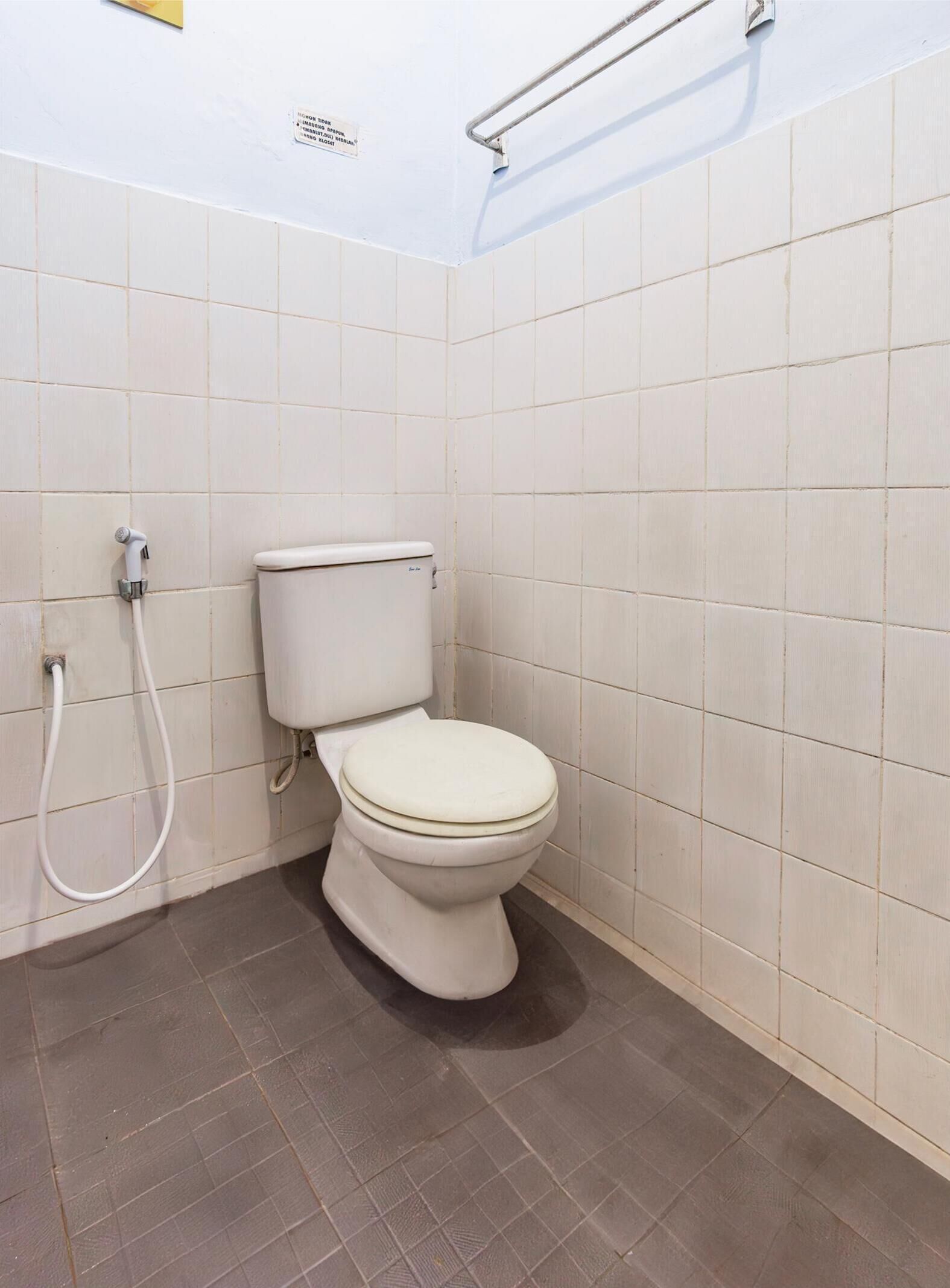 Une petite salle de bain propre, avec des carreaux blancs, des toilettes et une douche.