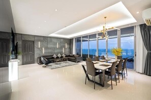 Uma sala de estar moderna com área de jantar, janelas amplas e vista para o oceano.