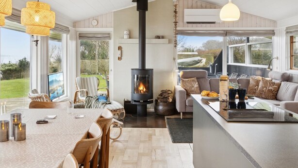 A modern living room with a central fireplace, a dining area with wooden chairs, and a kitchen with a large island. - "Titta" - 10m to the fjord by Interhome (Holbæk)