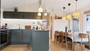 A modern kitchen with grey cabinets, a central island, and a dining area with wooden chairs and a table. - "Titta" - 10m to the fjord by Interhome (Holbæk)
