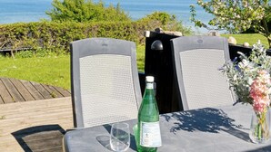 A table with two chairs, a bottle, and a glass on a deck overlooking a body of water. - "Titta" - 10m to the fjord by Interhome (Holbæk)