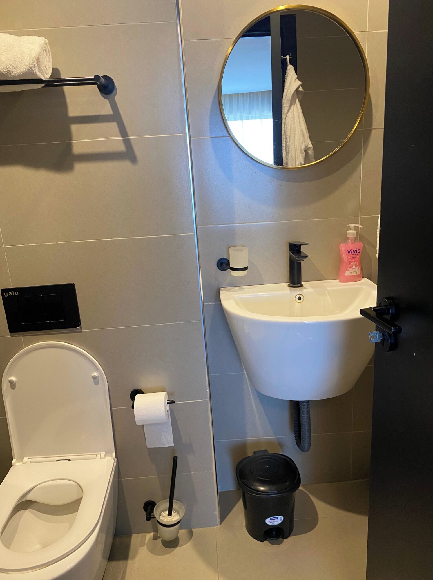 A modern bathroom with a toilet, sink, and mirror.