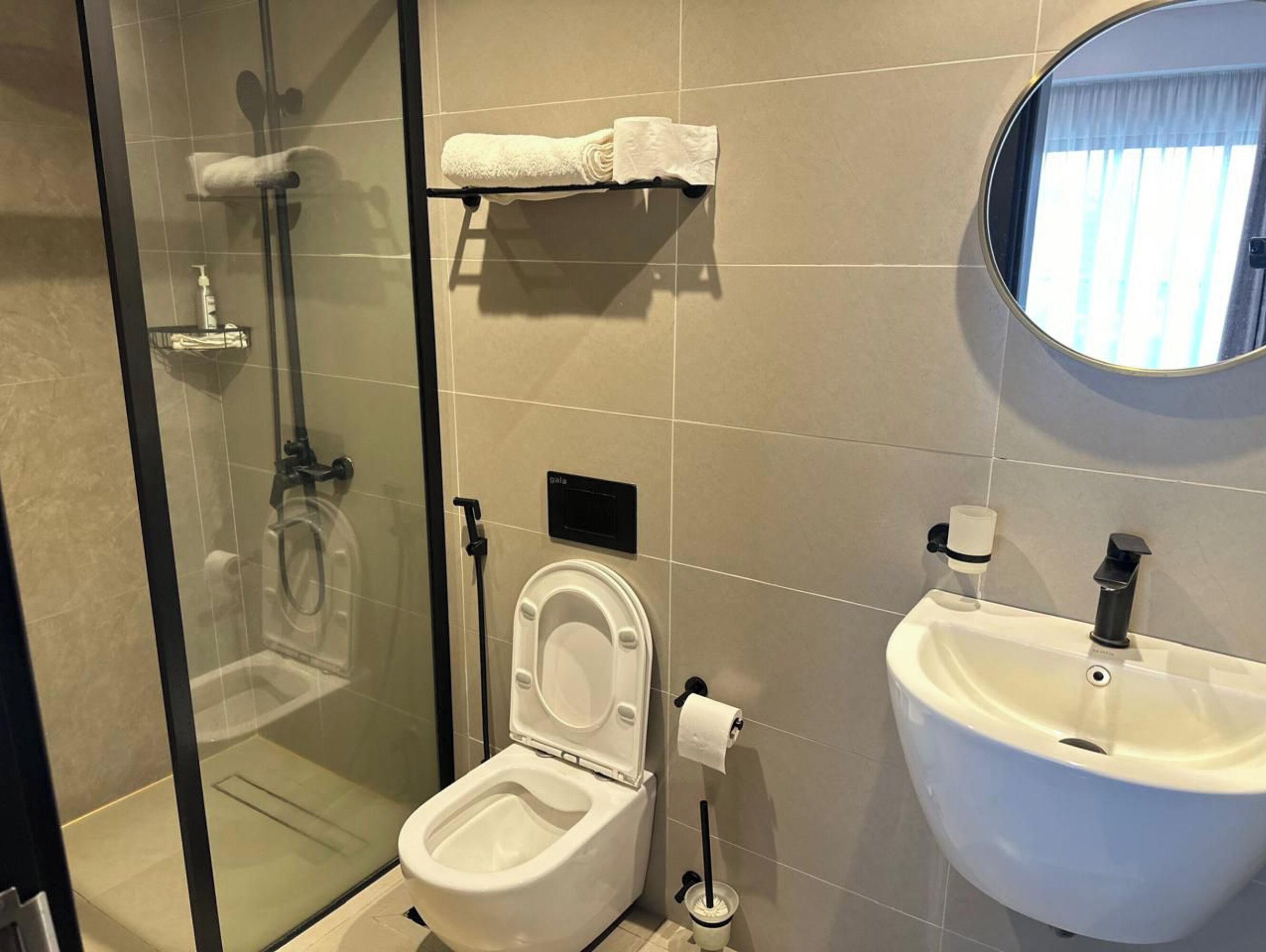 Un baño moderno con cabina de ducha de vidrio, inodoro, lavabo y espejo.