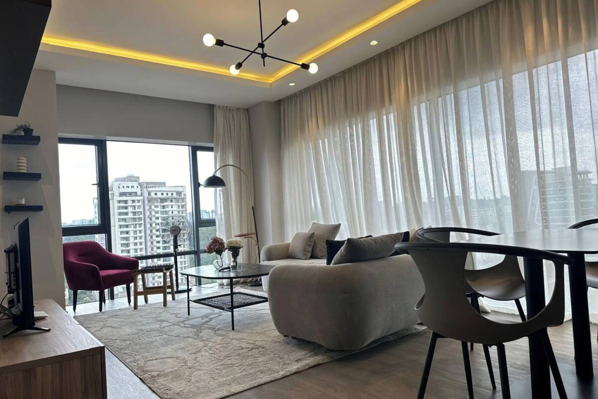 A modern living room with a sofa, armchairs, a coffee table, and a dining area.