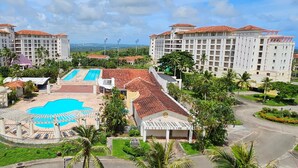 A resort with multiple buildings, a central swimming pool, and surrounding greenery.