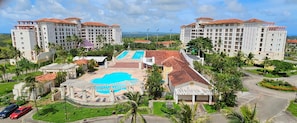 A resort with multiple buildings, a central swimming pool, and surrounding greenery.