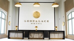 A reception area with a marble counter, gold accents, and a sign reading "LEOPALACE HOTEL".