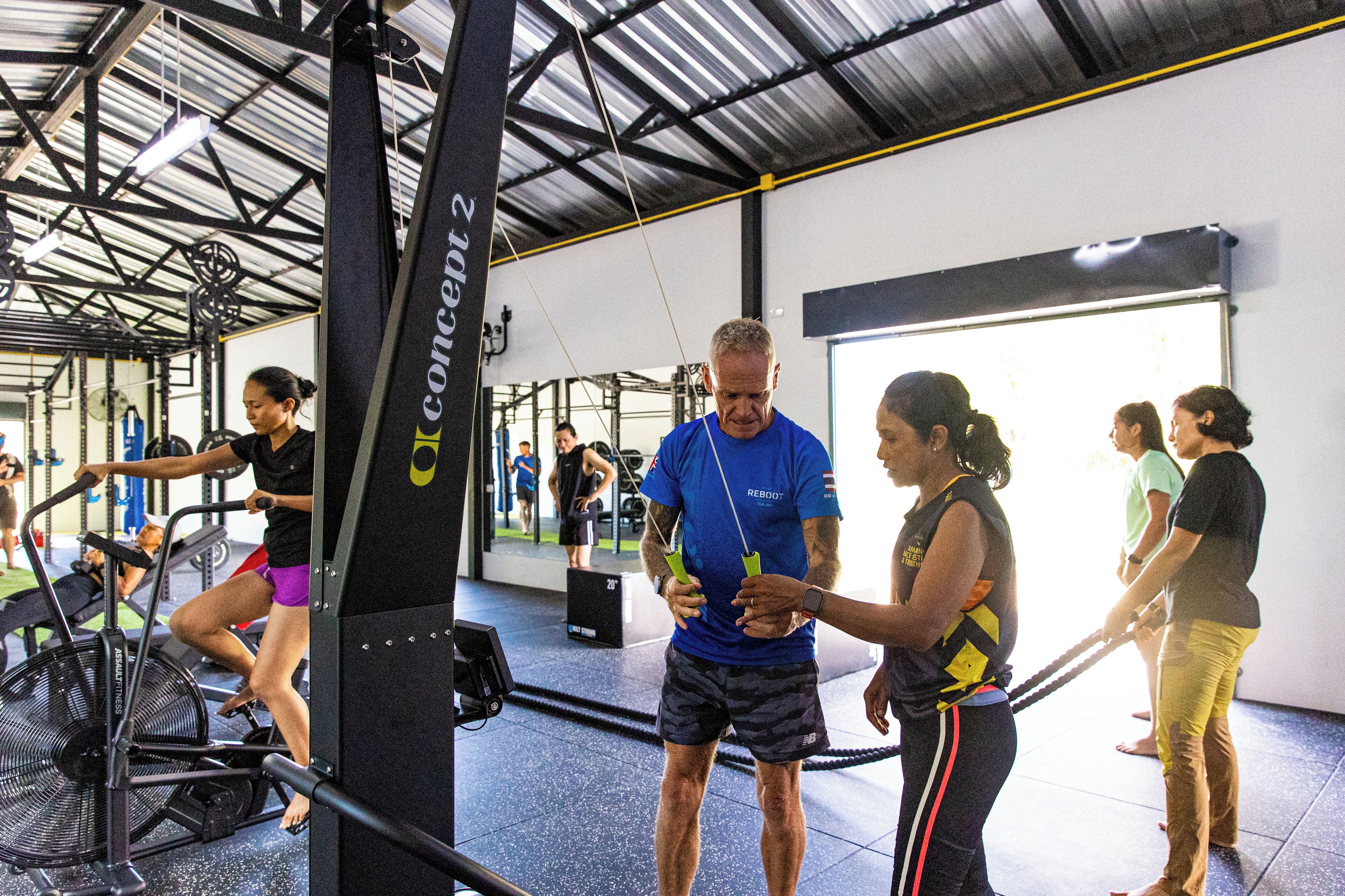 A gym with exercise equipment, a mirrored wall, and a ceiling with metal beams.