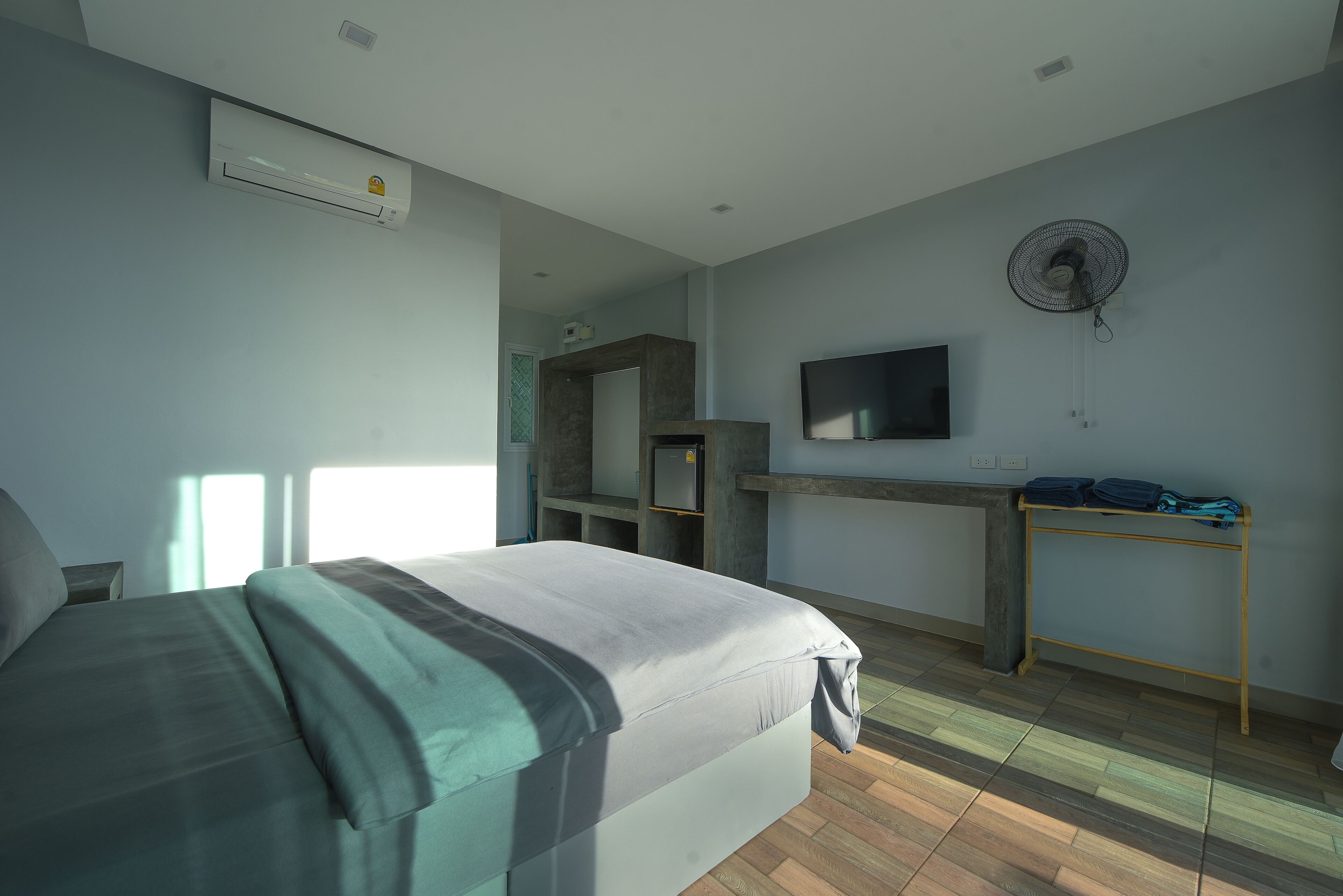 Un dormitorio con cama, escritorio, televisión y aire acondicionado.