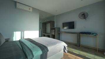 Un dormitorio con cama, escritorio, televisión y aire acondicionado.