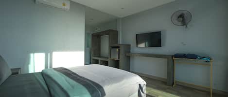 A bedroom with a bed, a desk, a TV, and an air conditioner.