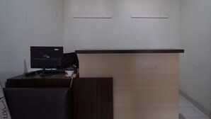 Een receptiebalie met een computer, een printer en een klein tafeltje met toetsenbord en muis.