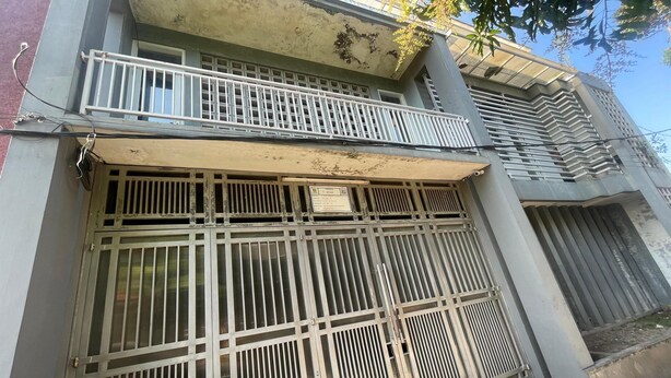 Een gebouw met een metalen poort, een balkon en een trap naar een verdieping.