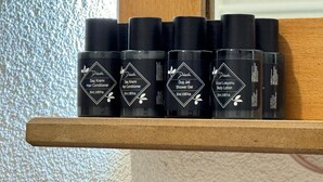 A shelf with black bottles of hair conditioner, shower gel, and body lotion. - Abelia Mansion Hotel (Istanbul)