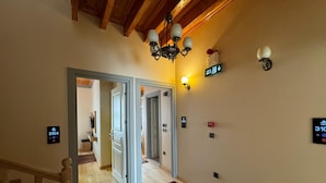 A hallway with a patterned carpet, wooden ceiling beams, and wall-mounted light fixtures. - Abelia Mansion Hotel (Istanbul)
