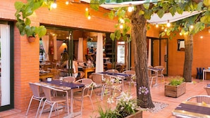 An outdoor patio area with brick walls, tables, chairs, and string lights.