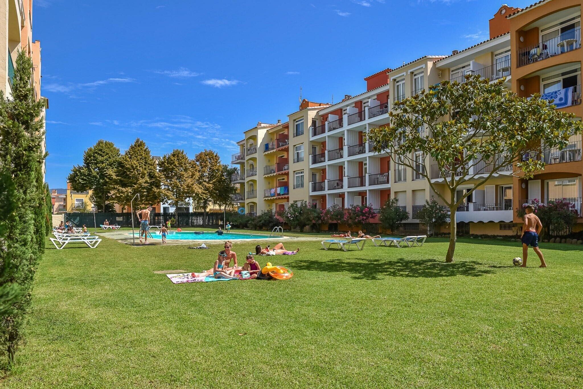 A courtyard with a swimming pool, lounge chairs, and a grassy area.