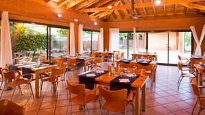 A spacious dining area with multiple tables and chairs, large windows, and a wooden ceiling. - Home Stay Steps from Sand (Cambrils)