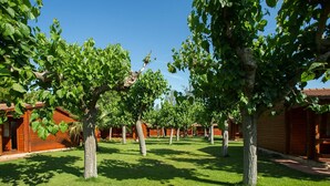 A row of wooden cabins with a well-maintained lawn and trees in front. - Home Stay Steps from Sand (Cambrils)