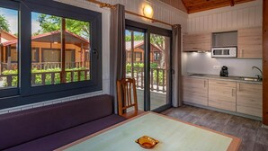 A modern kitchen with a built-in microwave, a dining area with a table and bench, and a sliding glass door leading to an outdoor deck. - Chalet in Blanes near the Beach & Pool (Blanes)