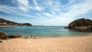 A beach with clear skies, calm water, and rocky outcrops. - Chalet in Blanes near the Beach & Pool (Blanes)