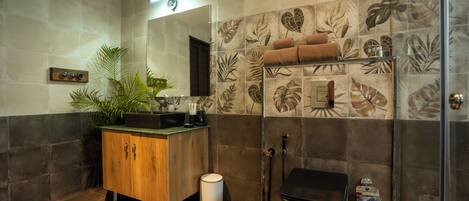 Un baño con tocador de madera, espejo, ducha y azulejos decorativos.