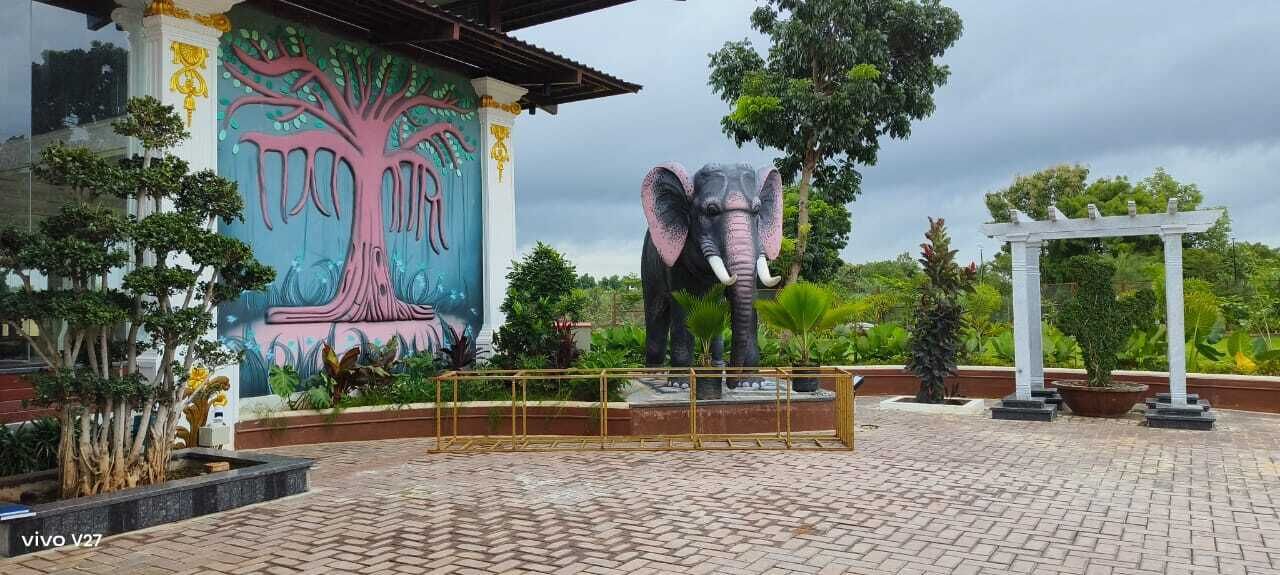A large elephant statue in front of a building with a colorful mural.