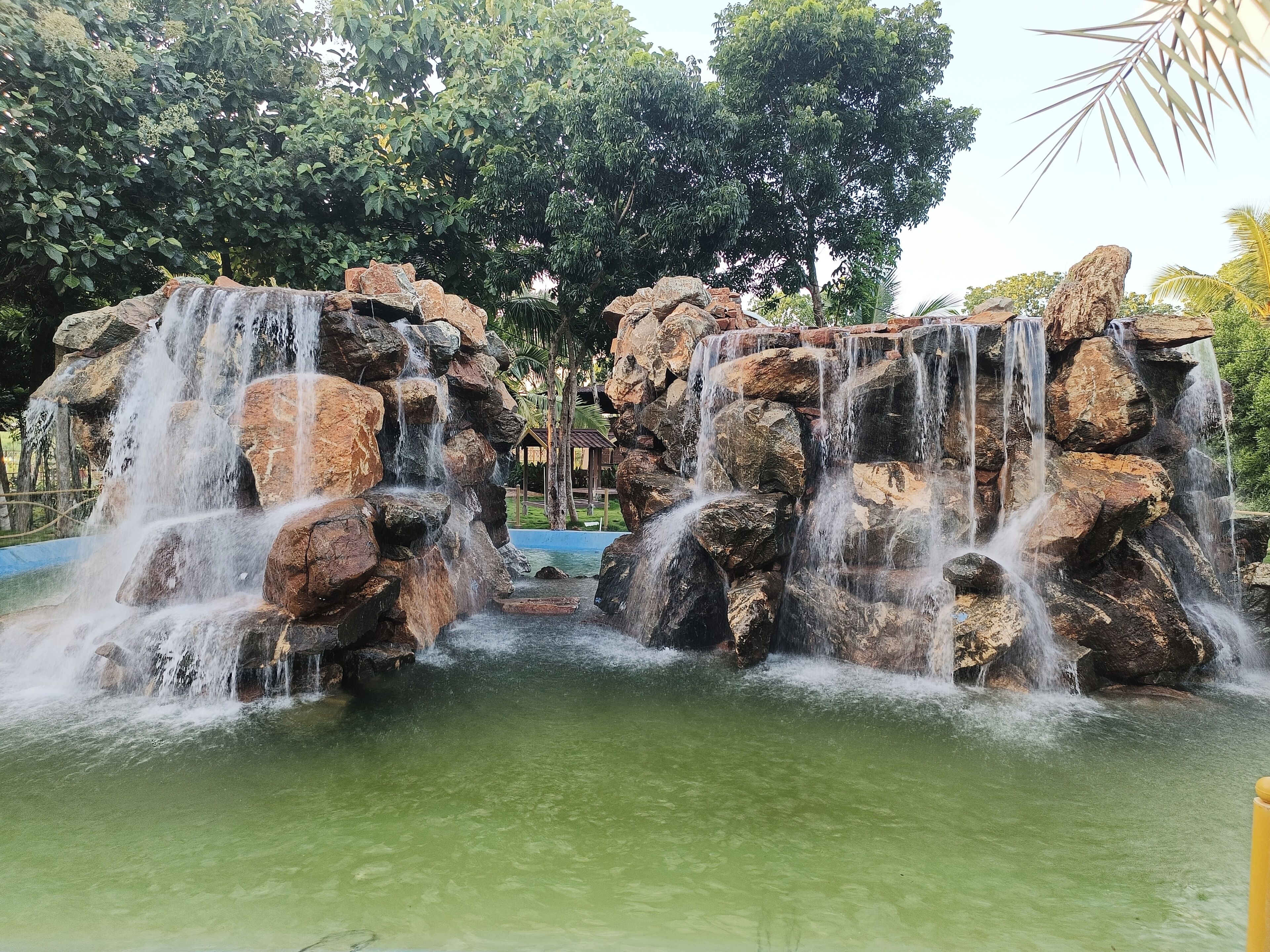 A waterfall feature with multiple tiers of rocks and water cascading down into a pool.