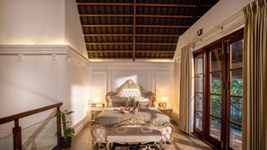 Un dormitorio con una cama grande, techo de madera y vistas al exterior con vegetación.