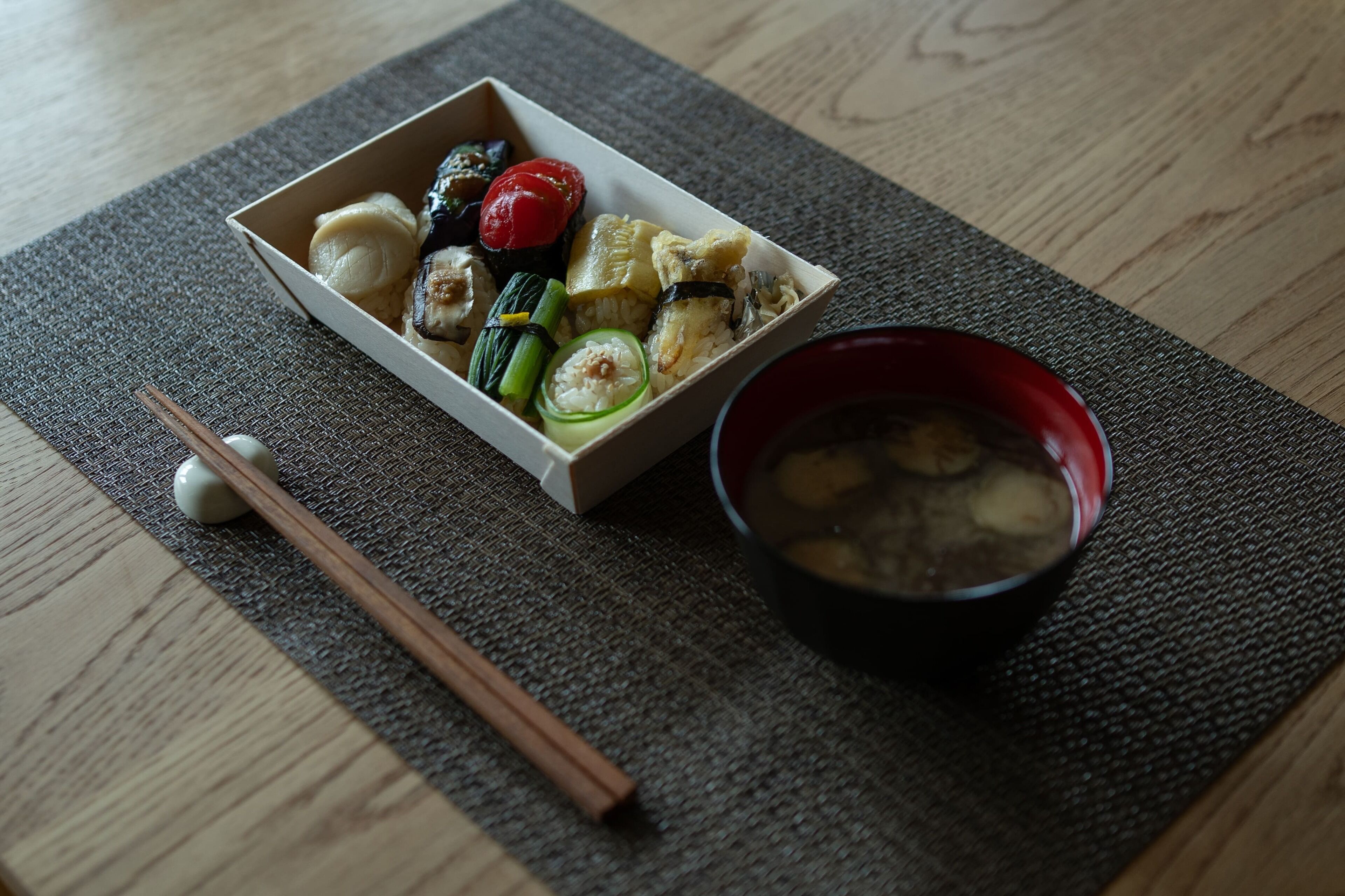A meal with various dishes and a bowl of soup on a textured mat.