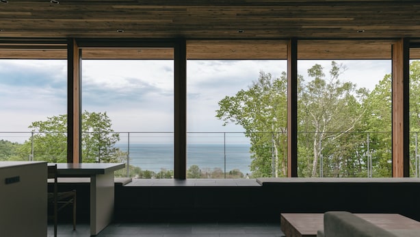 A modern interior with large windows offering a view of the sea and trees. - SANGO (Otaru)