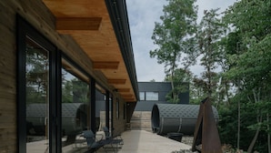 A modern building with large glass windows, a wooden deck, and outdoor seating. - SANGO (Otaru)