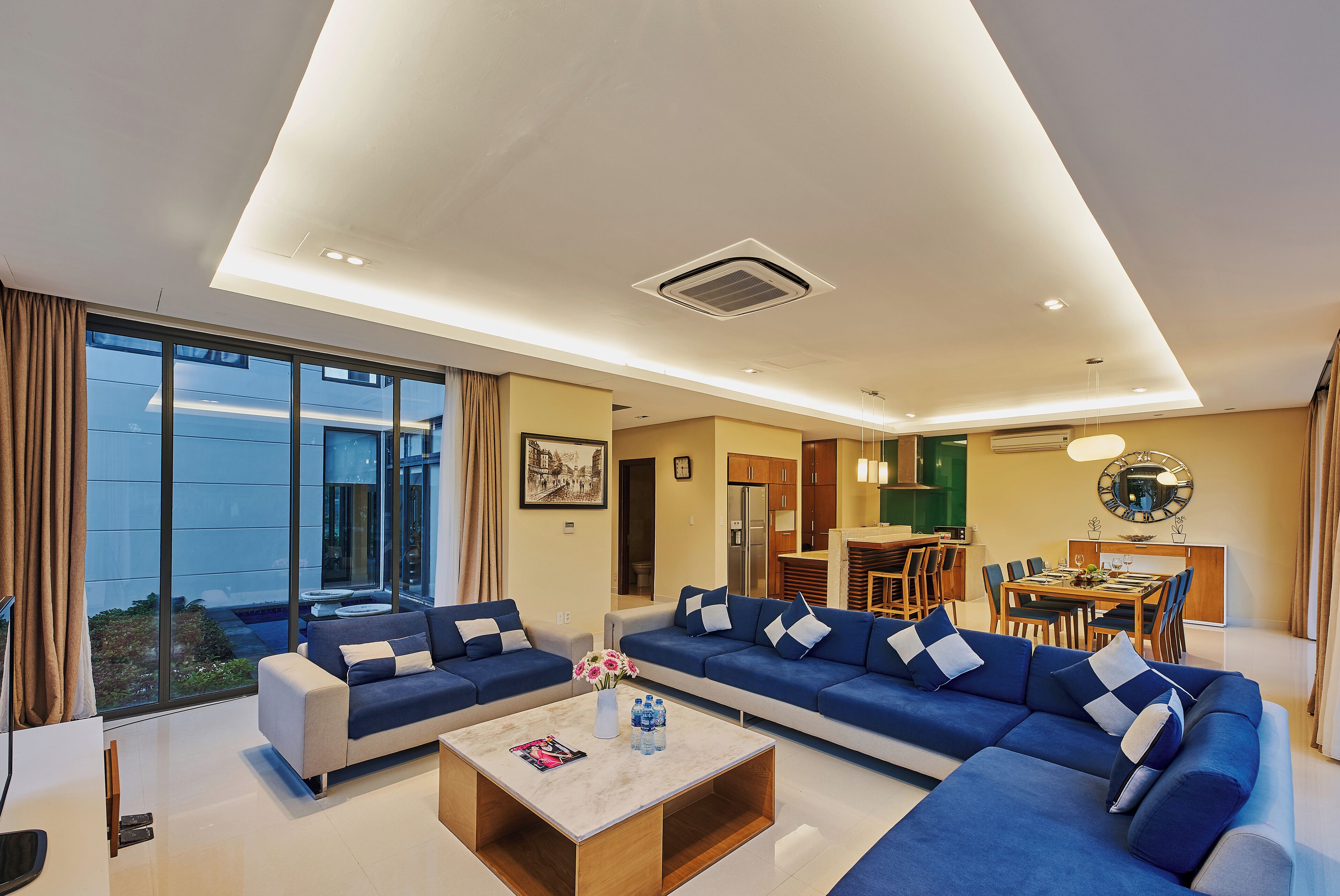 A modern living room with a sectional sofa, a coffee table, and a dining area with a table and chairs.