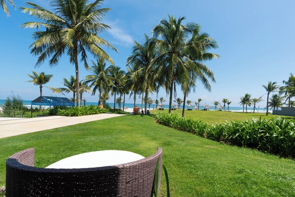 A grassy pathway leading to a beach with palm trees and a sign for the Activities Center. - Danang Private Swimming Pool Villa (Da Nang)