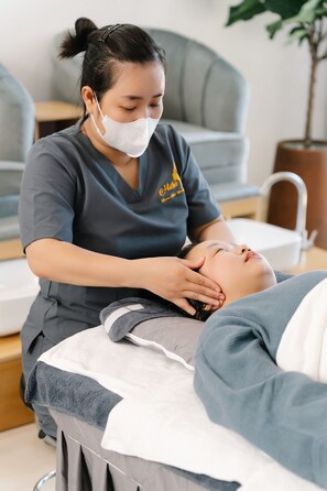 A person receiving a massage in a room with a grey sofa and a plant in the background. - Danang Private Swimming Pool Villa (Da Nang)