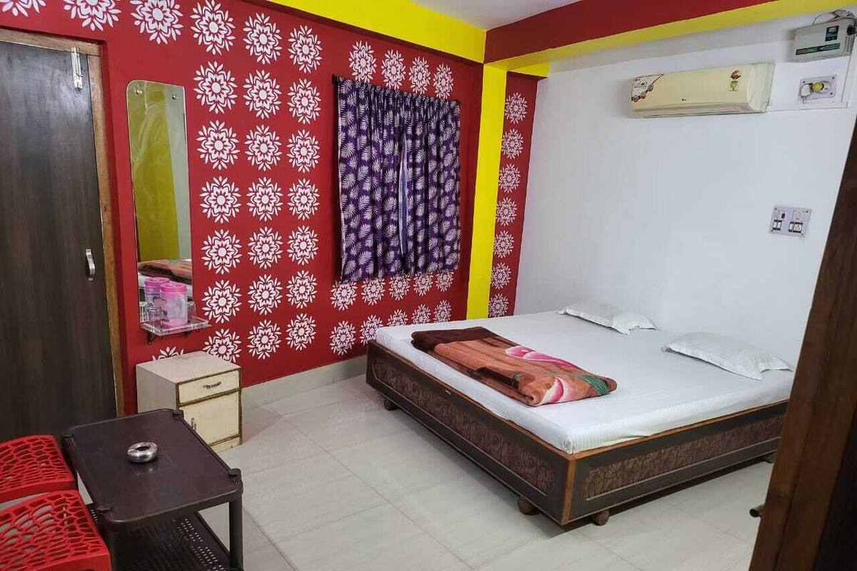 Une chambre à coucher comprenant un lit, une petite table, une chaise, une armoire et un climatiseur fixé au mur.