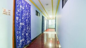 A hallway with blue walls, a red carpet, and a patterned blue curtain. - Hotel Nilay By GRB (Kahalgaon)