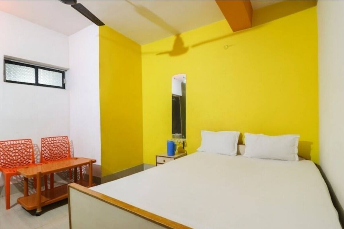 Une pièce comprenant un lit, une petite table, deux chaises et une fenêtre.
