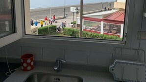 Eine Küche mit einem großen Fenster mit Blick auf einen Strand und ein Gebäude.