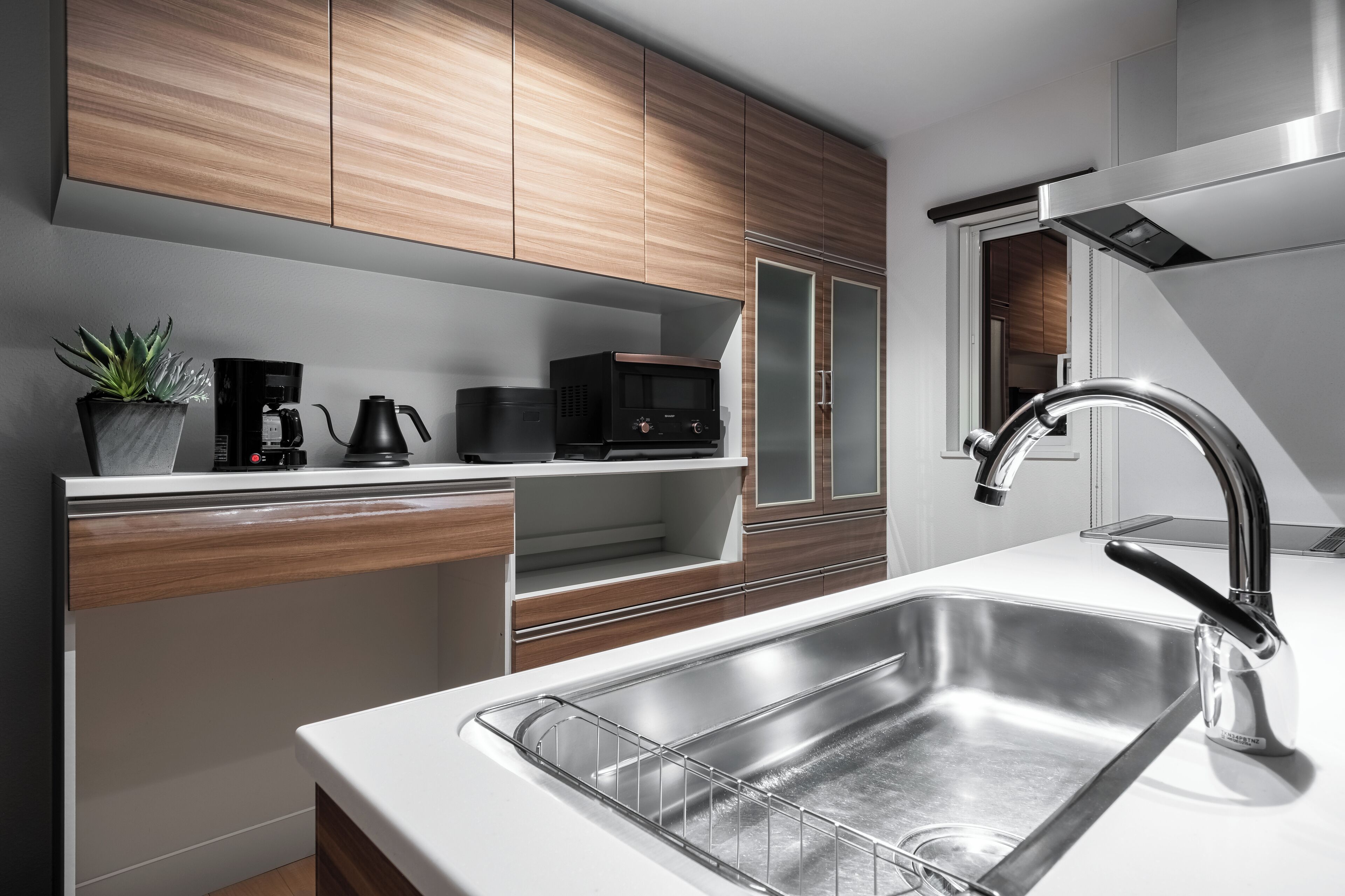 A modern kitchen with wooden cabinets, a stainless steel sink, a coffee maker, and a microwave.