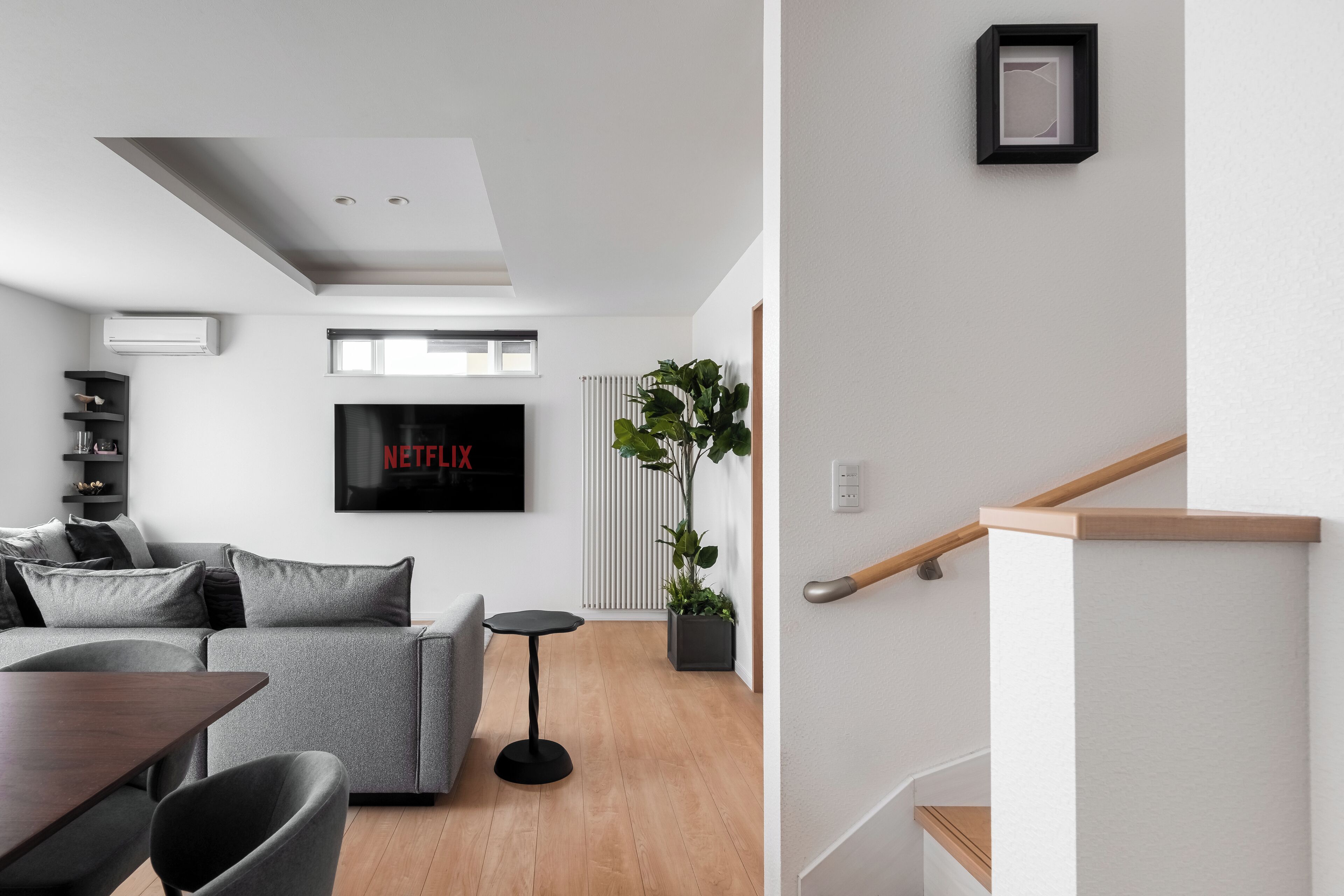 A modern living room with a grey sofa, a small round table, and a staircase with wooden steps.