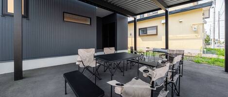 An outdoor patio with a table and chairs, a bench, and a covered area with a metal roof.