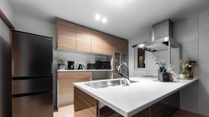 Eine moderne Küche mit einem Edelstahl-Kühlschrank, Holzschränken, einer weißen Arbeitsplatte und einem Edelstahl-Spülbecken.