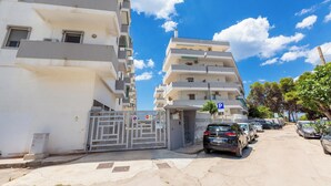 A residential building with a gated entrance, multiple balconies, and parked cars along the street. - 4146 Giò House by Barbarhouse (Gallipoli)