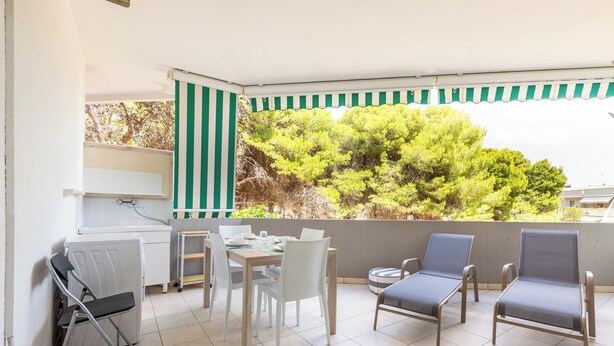 A balcony with a view of green trees, a dining table with chairs, and two lounge chairs. - 4146 Giò House by Barbarhouse (Gallipoli)