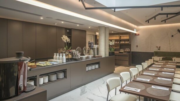 A modern dining area with a buffet setup, long tables, and a seating arrangement. - Palazzo Vittoria Hotel Milano (Milan)